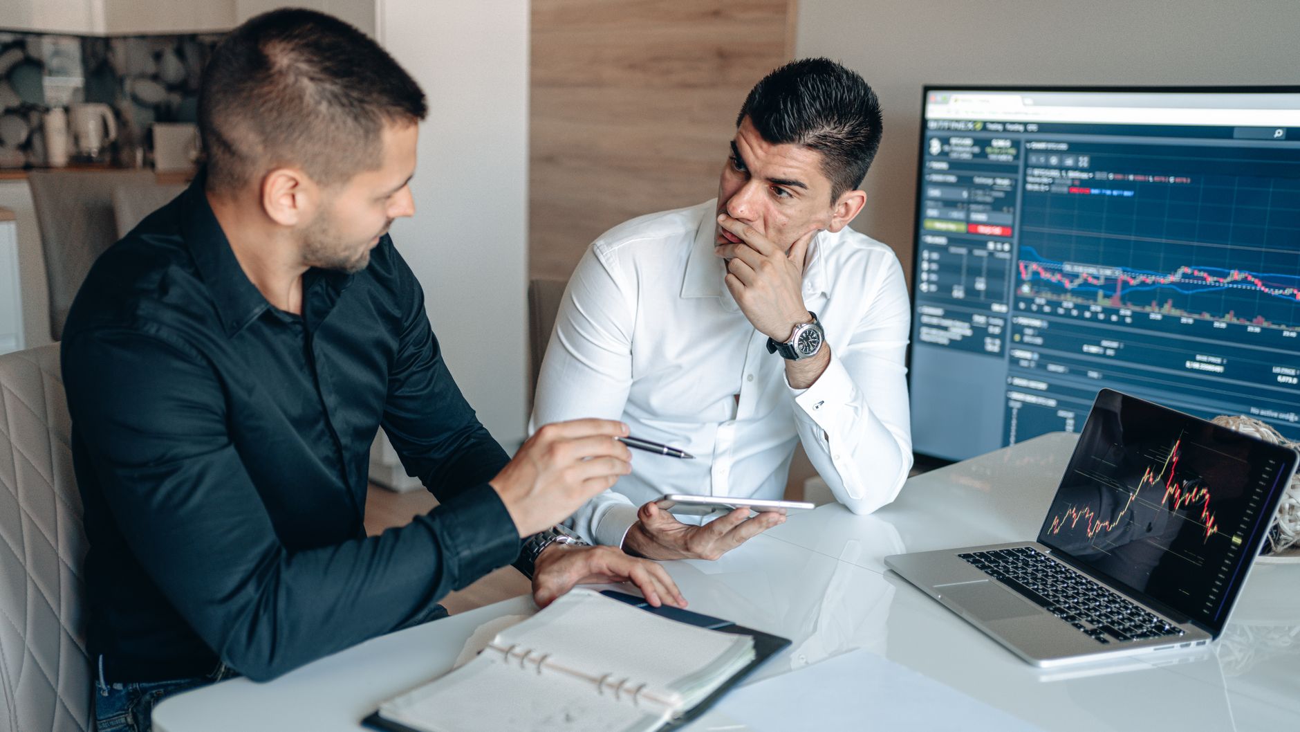 Colleagues discussing plans over a digital workspace showing reports